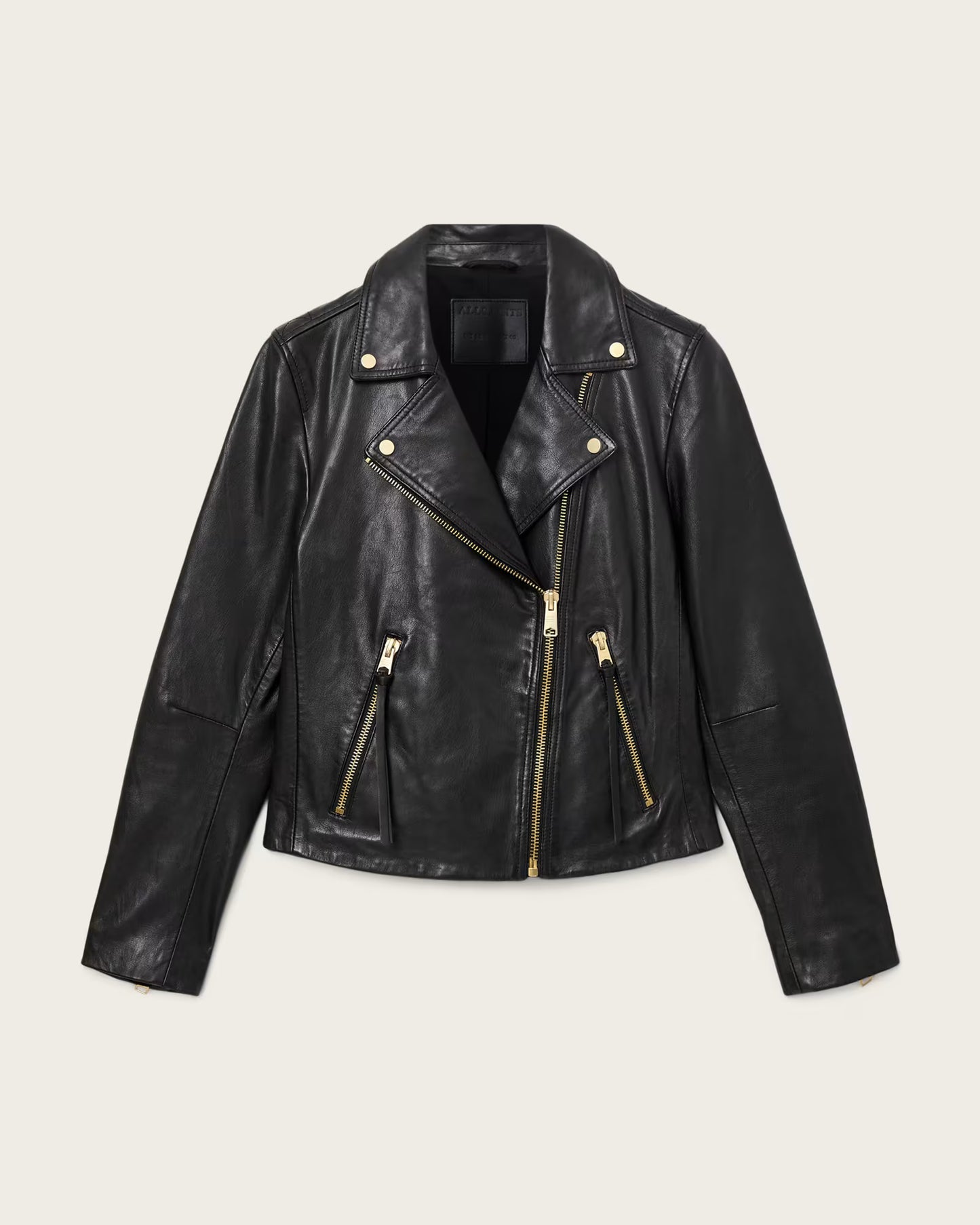 Black leather jacket with gold zippers on a light beige background