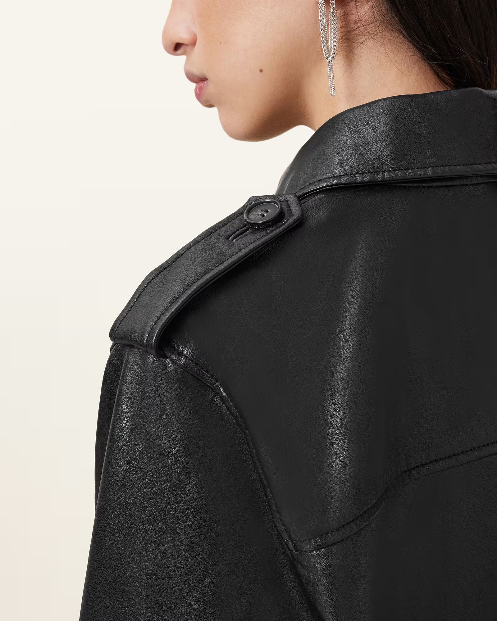 Close-up of a person wearing a black leather jacket on a beige background