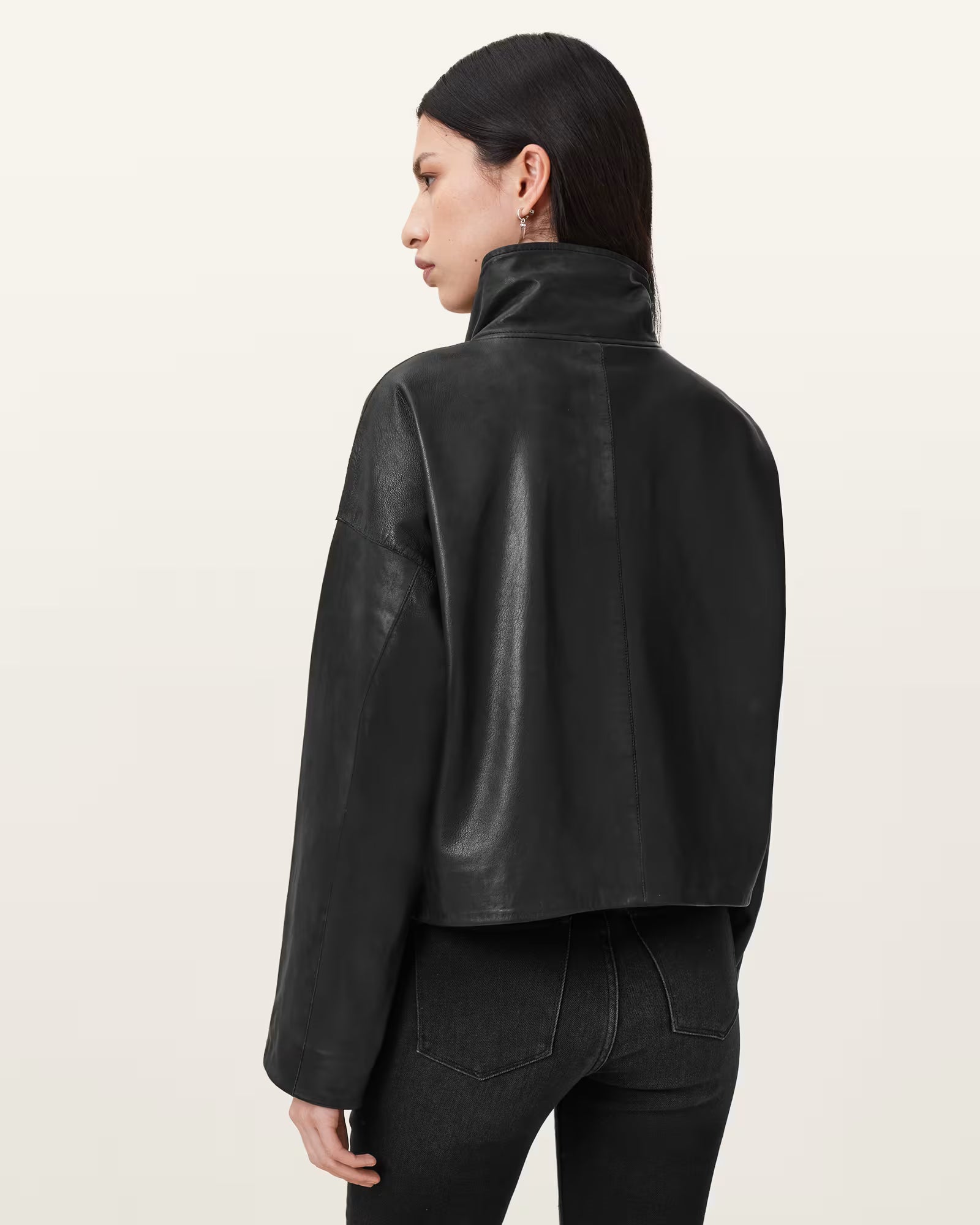 Person wearing a black leather jacket on a plain background