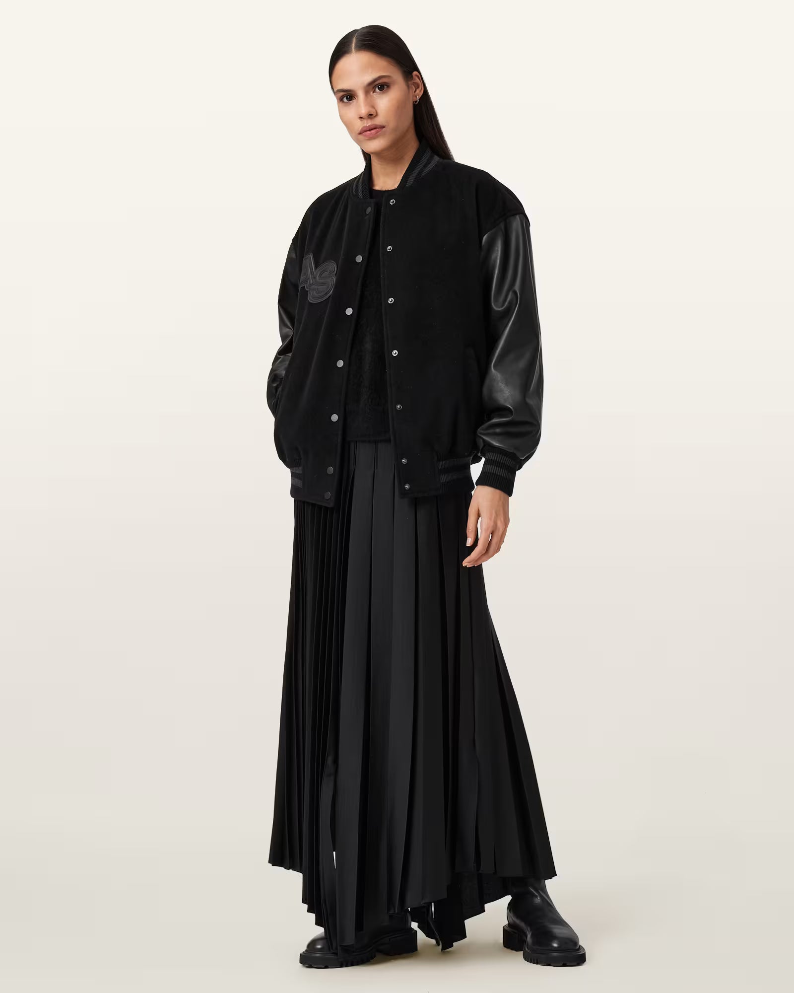 Person wearing a black outfit with a pleated skirt on a white background