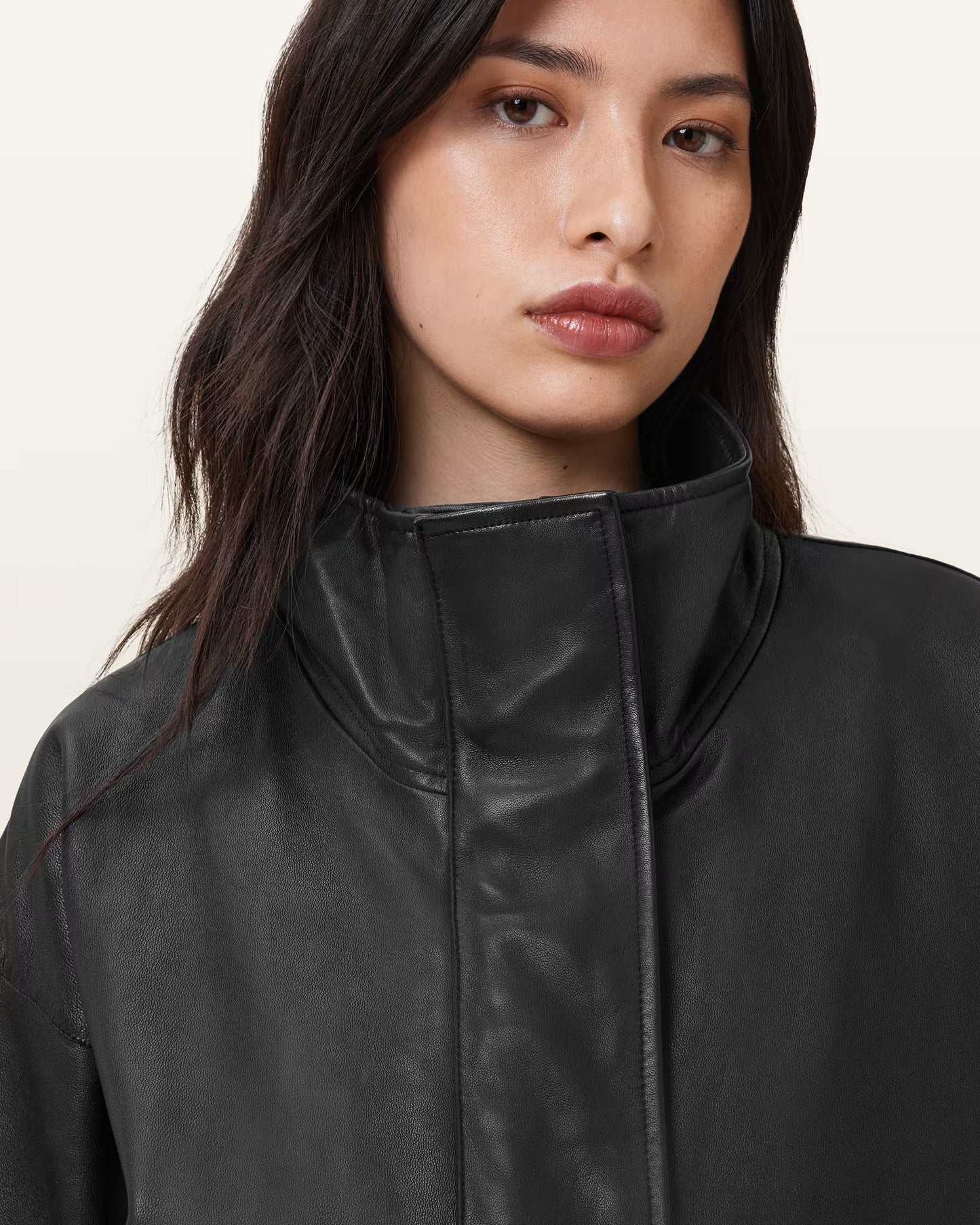 Woman wearing a black leather jacket against a plain background
