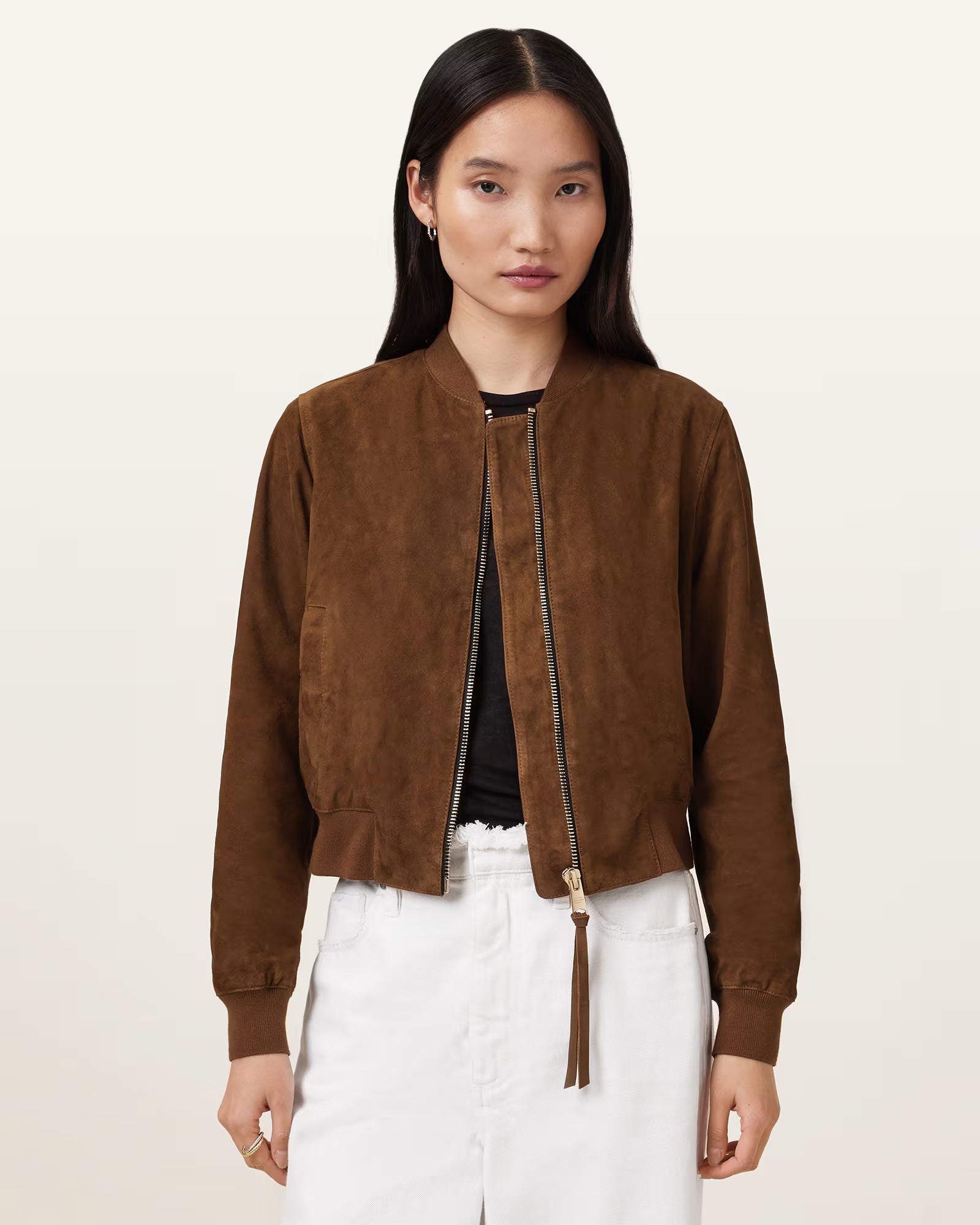 Woman wearing a brown suede jacket on a beige background