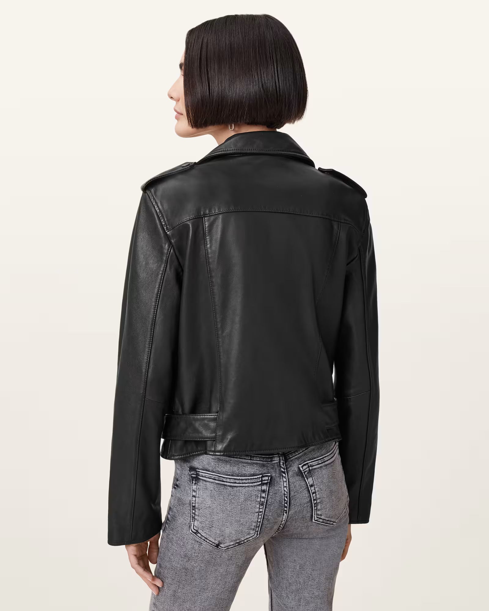 Person wearing a black leather jacket on a beige background