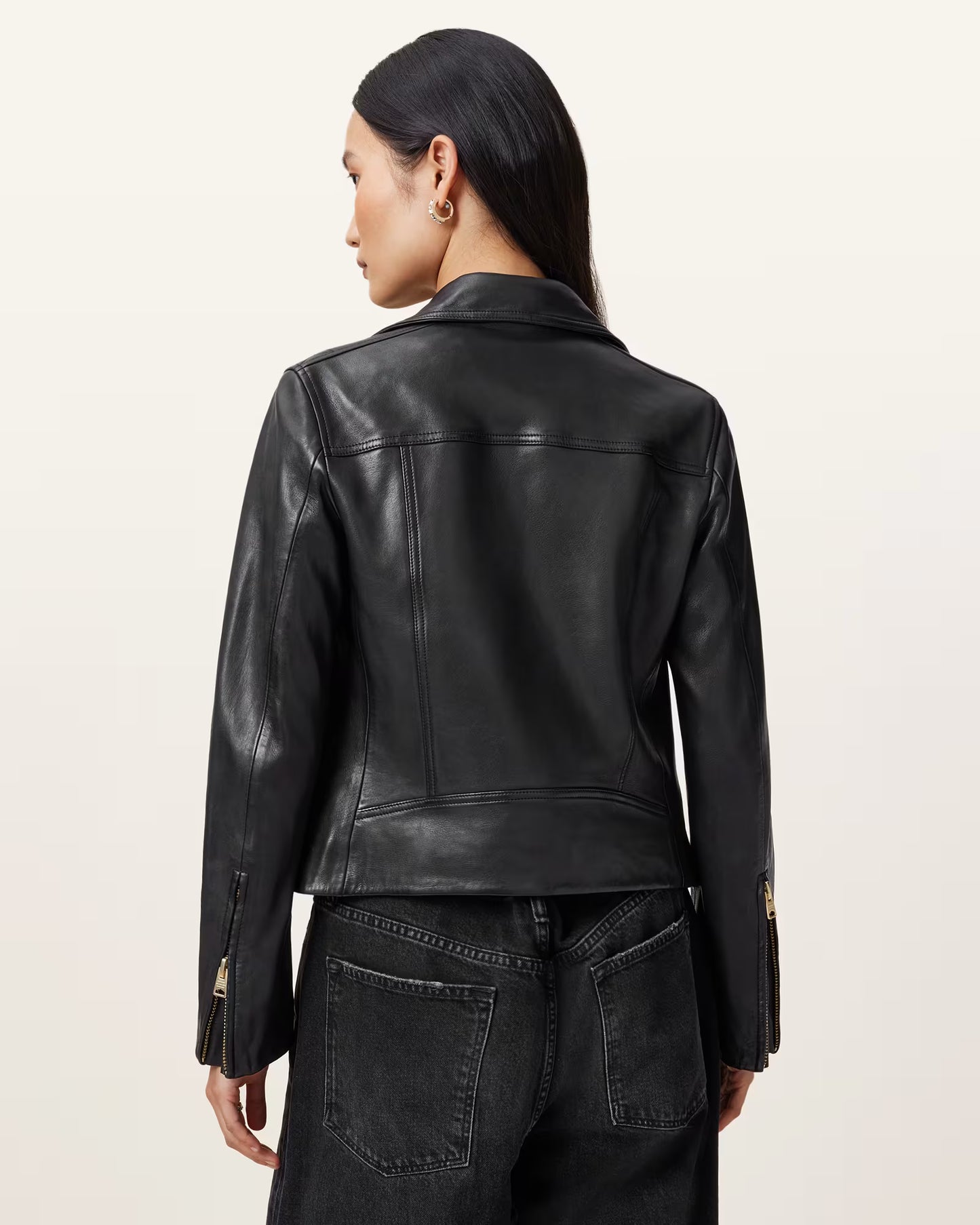Person wearing a black leather jacket on a beige background