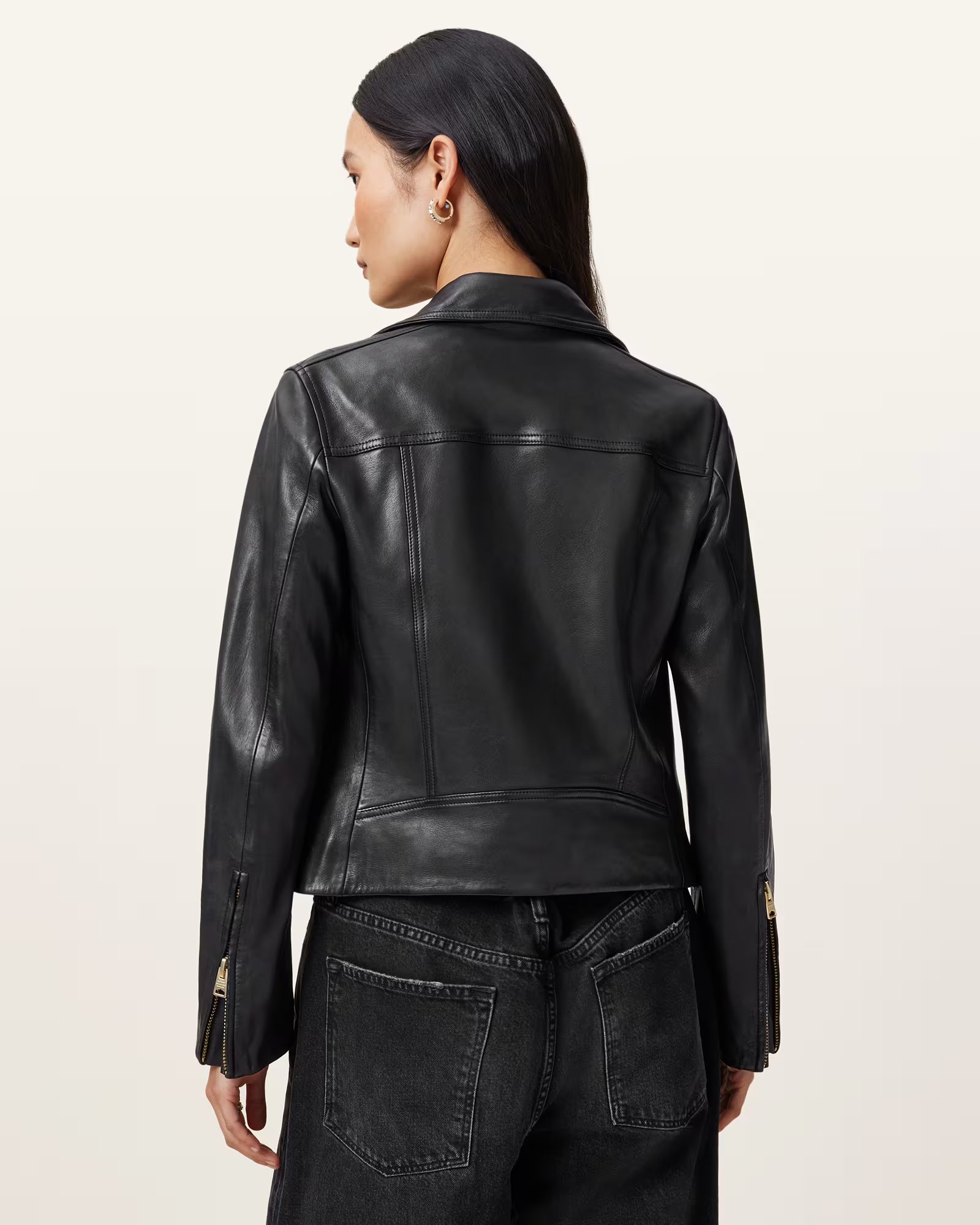 Person wearing a black leather jacket on a beige background