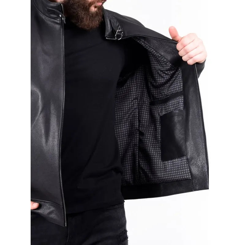 Person wearing a black leather jacket with a textured inner lining, holding it open to show the interior.