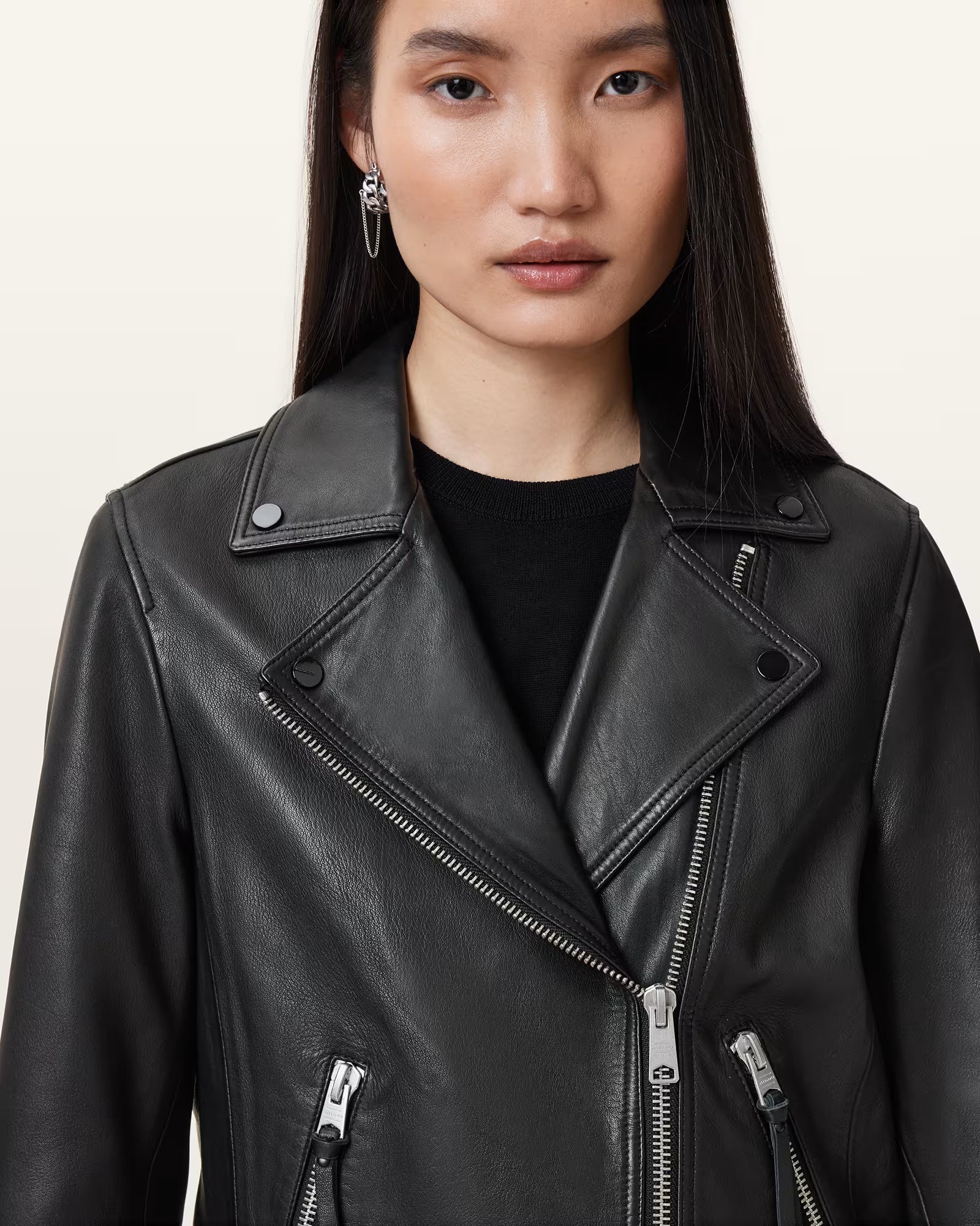 Person wearing a black leather jacket on a plain background