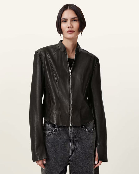 Woman wearing a black leather jacket and jeans on a beige background