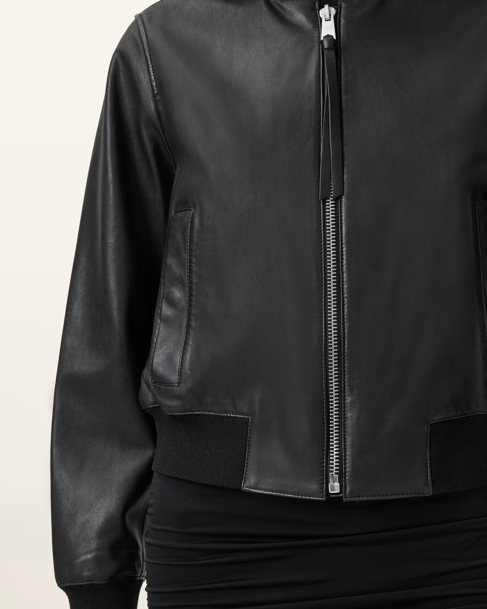 Black leather jacket with a zipper on a neutral background