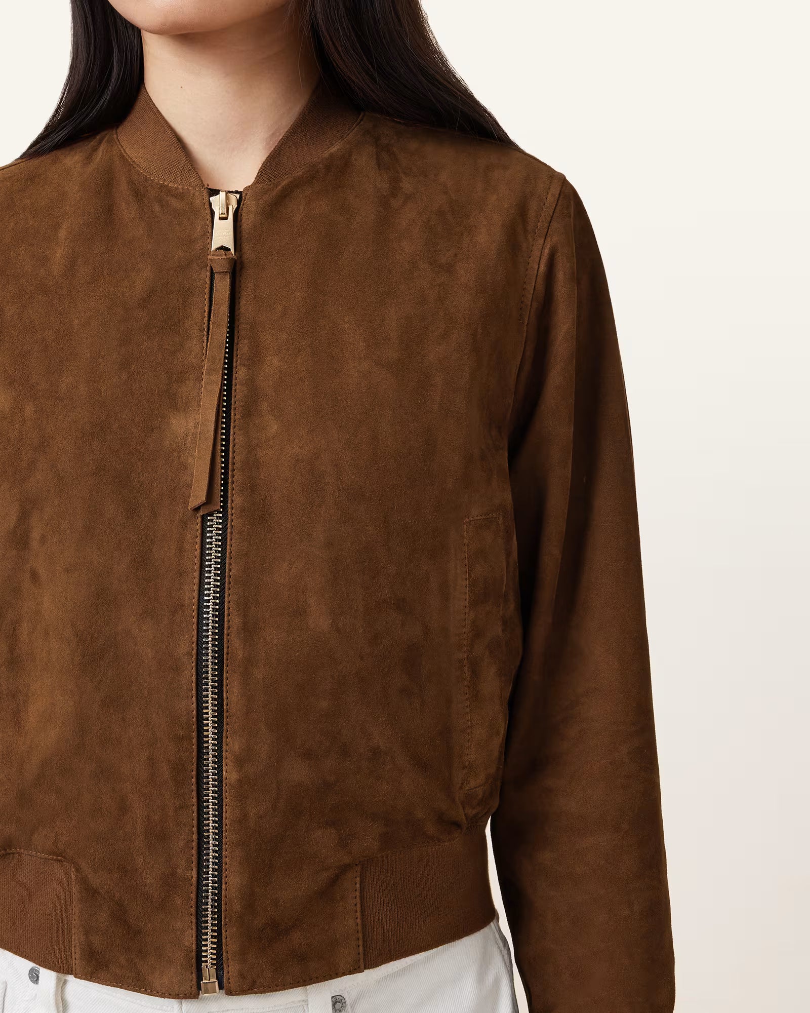 Brown suede jacket with a zipper on a neutral background