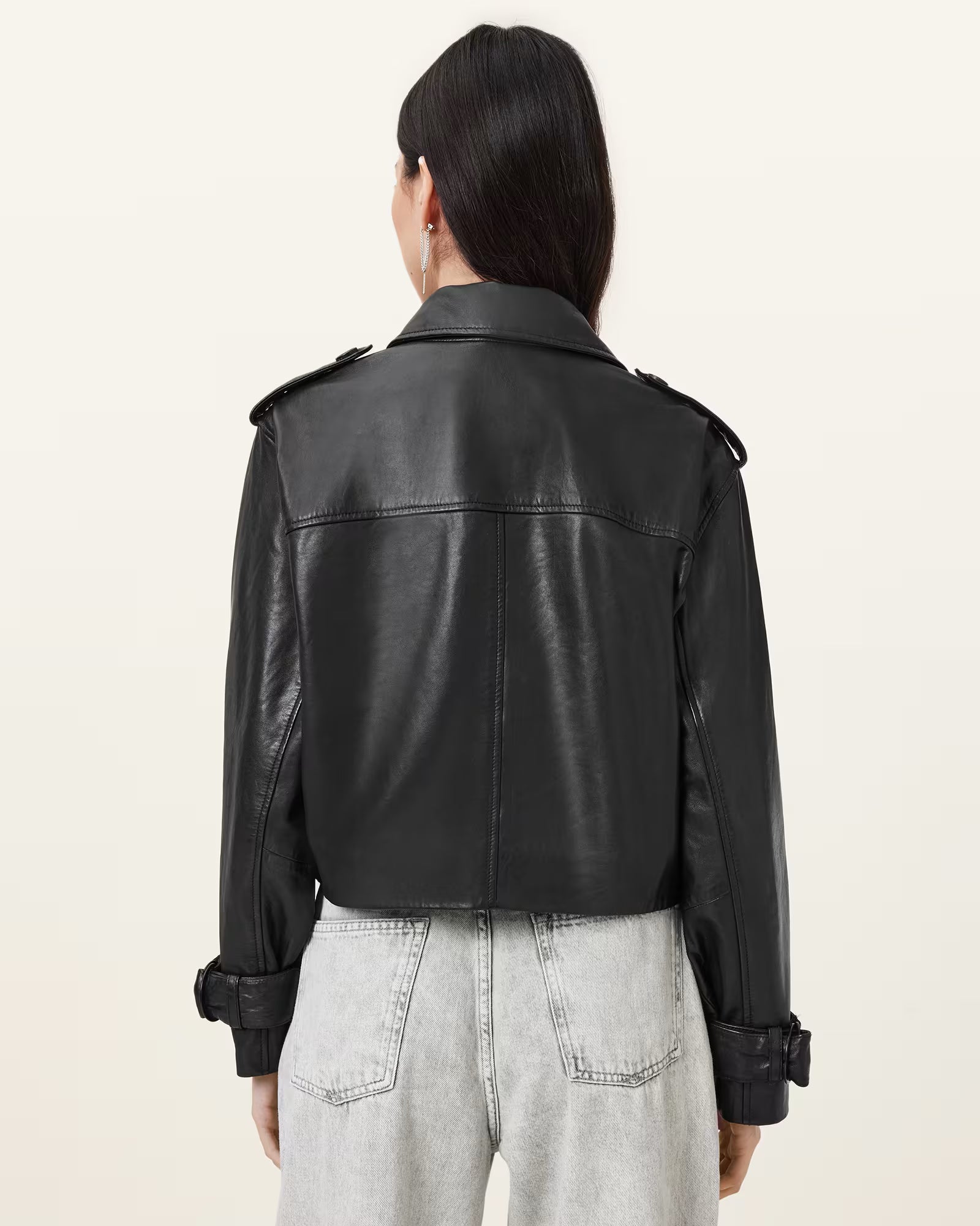 Person wearing a black leather jacket on a plain background