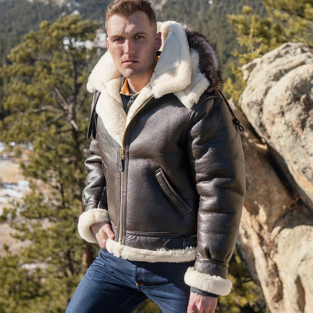Man wearing a leather jacket with white fur lining in a mountainous area