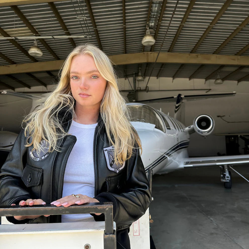 Woman standing in front of a small airplane inside a hangar