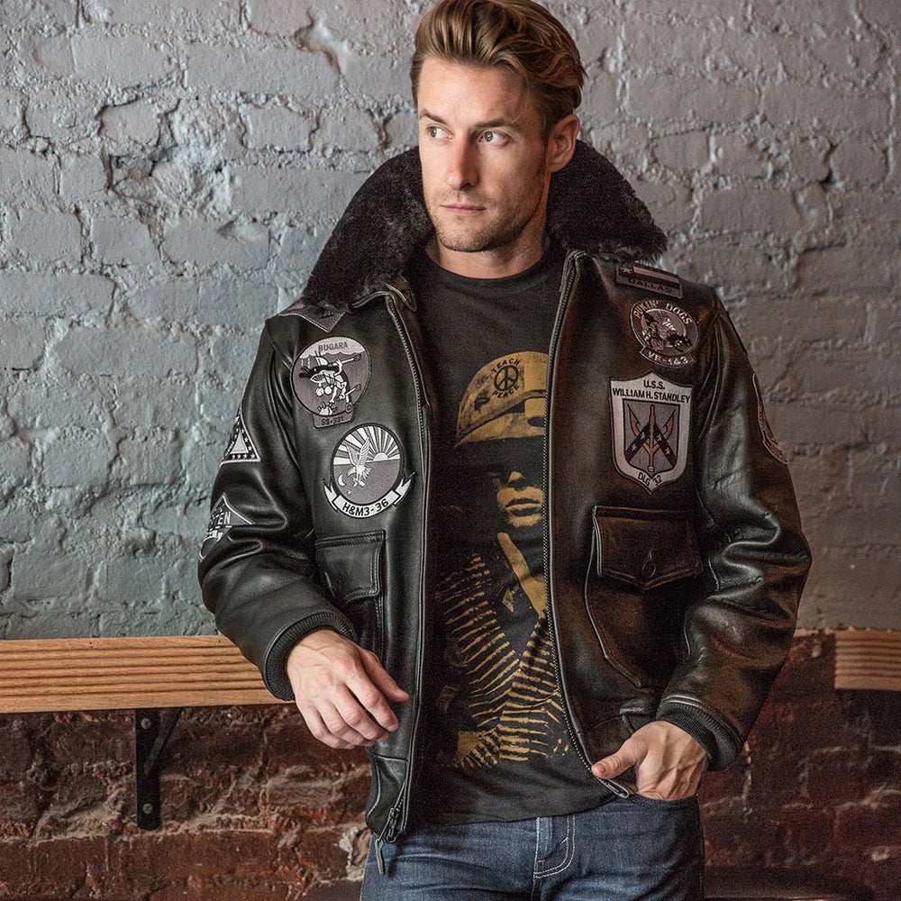 Man wearing a leather jacket with patches against a brick wall.