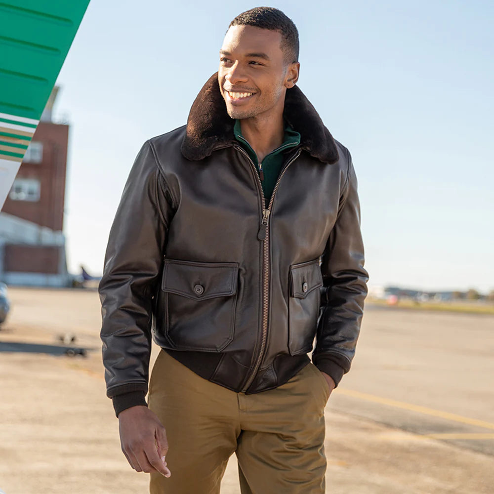 Man wearing a brown leather jacket with fur collar on an airport tarmac.